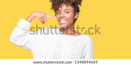 Beautiful young african american woman wearing winter sweater over isolated background Pointing with hand finger to face and nose, smiling cheerful