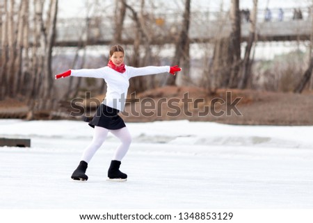 beautiful young woman on the open rink on skates in a white suit