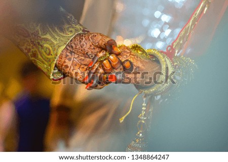 Bride and Groom (with henna hands) locked hands together by following marriage rituals in india