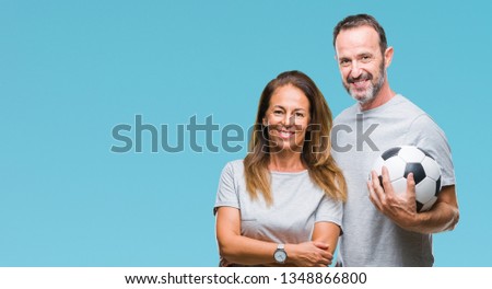 Middle age hispanic couple holding football soccer ball over isolated background with a happy face standing and smiling with a confident smile showing teeth