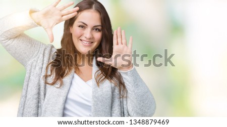 Beautiful plus size young woman wearing winter jacket over isolated background Smiling doing frame using hands palms and fingers, camera perspective