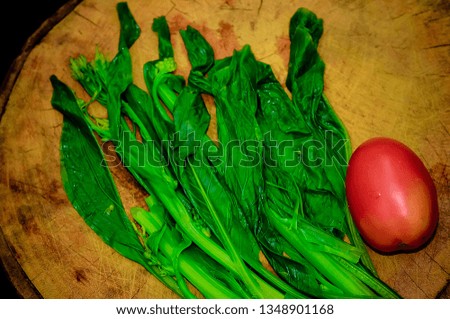 
Red tomatoes And green vegetables On brown wood