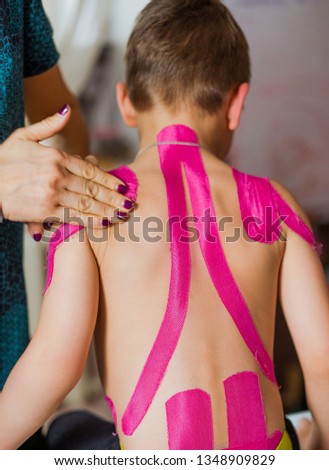 Physiotherapist is taping little boy's back. Rehabilitation