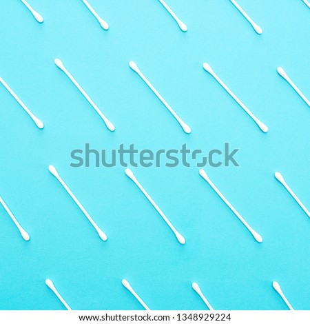 White cotton buds lie in a row on a blue background. Beautiful background