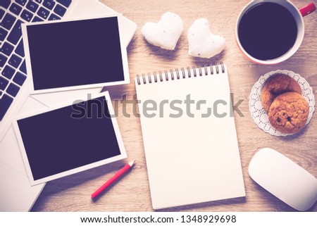 Laptop with coffee cup photos and pen on wooden table 