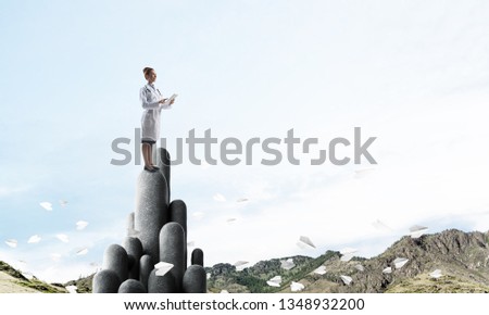 Young female doctor with folder in hands satnding on stone column