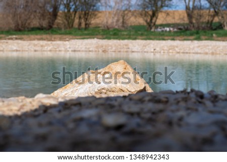 Rock in sunlight with water in lake in background