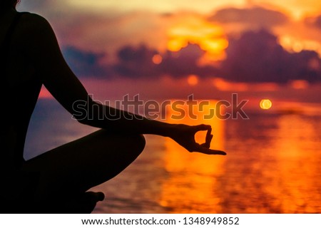Woman meditating, relaxing in yoga pose at sunset, zen meditation. Silhouette in lotus pose. Mind body spirit concept Royalty-Free Stock Photo #1348949852