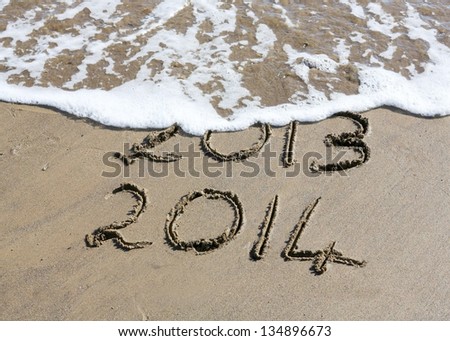  New Year 2014 is coming concept - inscription 2013 and 2014 on a beach sand, the wave is starting to cover the digits 2013 Royalty-Free Stock Photo #134896673