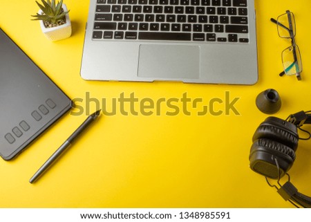 Desktop designer, and creative retoucher with a graphics tablet, laptop, glasses. Design, flat lay. On a yellow background