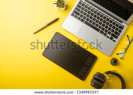 Desktop designer, and creative retoucher with a graphics tablet, laptop, glasses. Design, flat lay. On a yellow background