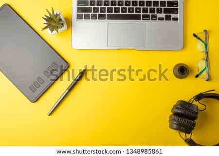 Top view of the workplace designer. Creative designer, graphics tablet, laptop, and accessories for the graphic designer.Flat lay.On yellow background