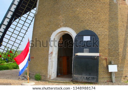 Waving national flag at typical Dutch corn windmill, Betuwe, Netherlands. Koningsdag (Kingsday) and Bevrijdingsdag (Liberation Day) celebrations