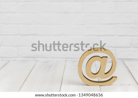 At sign on white wood table over white brick background with copy space.