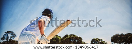 Side view of cricket player batting while playing on field against clear sky