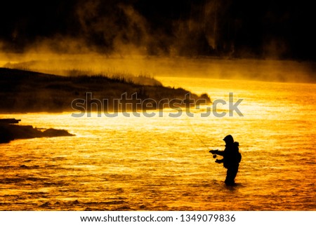 Silhouette of Fishing Flyfishing rod reel in river with golden sunlight early morning fisherman yellowstone river Royalty-Free Stock Photo #1349079836