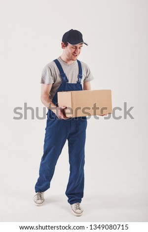Going to the customer with order. Guy with box in hands stands against white background in the studio.