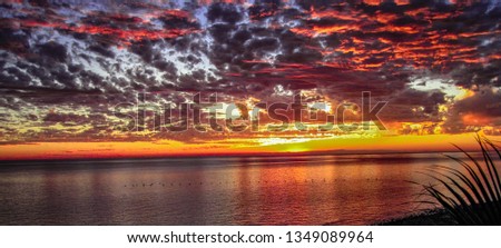 Beautiful sunset over the Sea Of Cortez (Gulf Of California) with water reflections on a calm sea and red, yellow, gold, orange, magenta and purple sky near Puerto Penasco (Rocky Point), Mexico