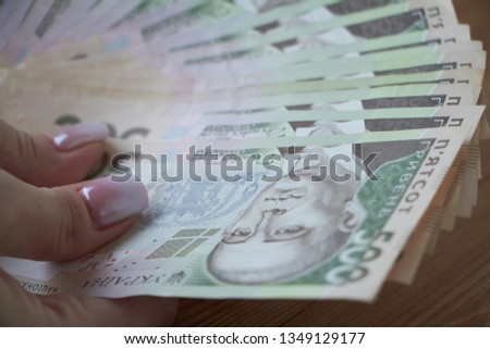 Ukrainian national currency, bills of different values, the calculation between people, the transfer of money, wood background.