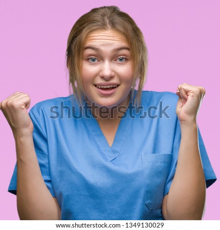 Young caucasian nurse woman wearing surgeon uniform over isolated background celebrating surprised and amazed for success with arms raised and open eyes. Winner concept.