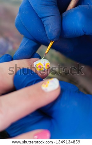 The process of creating a manicure, drawing on the nails. Preparing for a wedding or other holiday, close-up vertical format