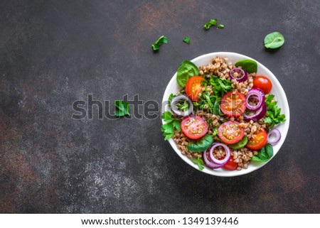 Buckwheat salad with vegatables and greens on black background, copy space. Heathy clean vegan raw food, fresh salad with buckwheat. Royalty-Free Stock Photo #1349139446