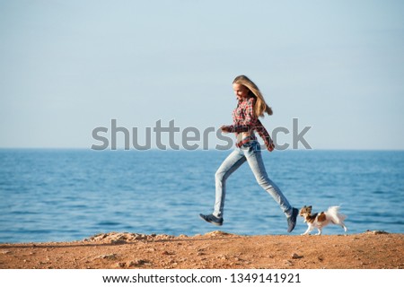 happy beautiful active young woman running together little chihuahua dog along sea shore