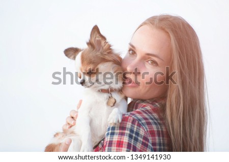 portrait of cute young girl with her little chihuahua pet dog on bright background