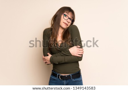 Young woman on ocher background making doubts gesture while lifting the shoulders