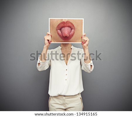 woman holding picture with big lips and tongue. concept photo over dark background