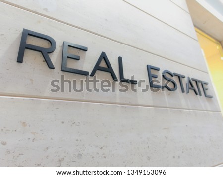 ¨Real estate¨is written in nice stylized black letters on a beige white stone building facade. Nice contrast.