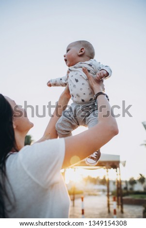 Beautiful young mother have fun with her little son at sunset