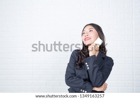 Business woman holding a separate cash card, white brick wall Made gestures with sign language.
