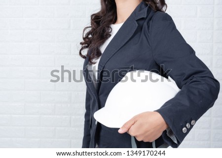 Woman of engineering holding a hat, Separate the white brick wall made gestures with sign language.