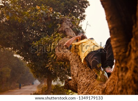 Young man smoking a cigarette lying on a parts of a tree