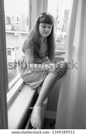 Beautiful caucasian girl with long hair wearing in red dress sitting on the window sill at home, portrait, white background