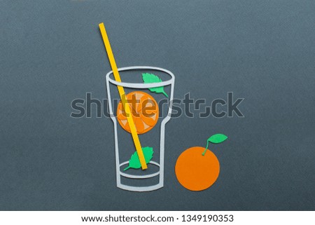 Orange lemonade with mint leaf in a glass tumbler. Cocktail tube. Paper art and cut. Handmade and colorful. On blue background. 