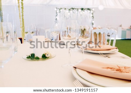 Wedding table service. Plates, glasses and flowers served on pink cloth