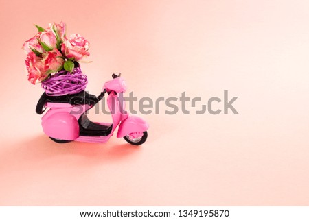 bouquet of roses in basket on backseat of cute pink scooter on pink background. Flower delivery.