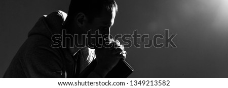 Religious young man praying to God on dark background, black and white effect Royalty-Free Stock Photo #1349213582