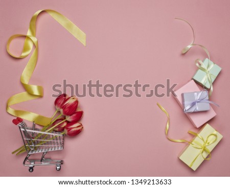 Shopping trolley, gift boxes, tulips flowers on a pink background. Top view with copy space. Valentine's day, Mother's day, Women's day, wedding and other festive events. Seasonal sale