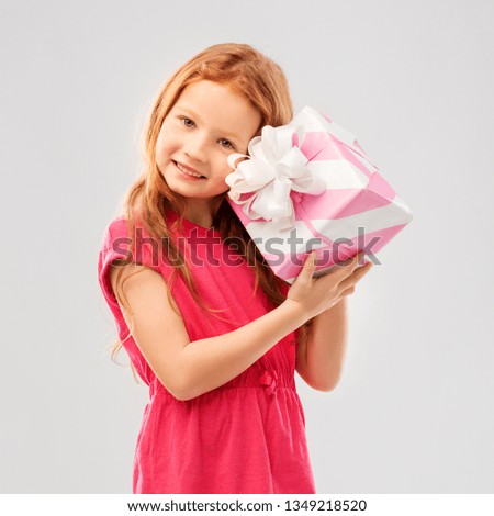 birthday and people concept - lovely red haired girl with gift box over grey background