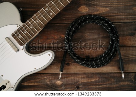 Guitar electric rock background. Cable jack on wooden table, top view