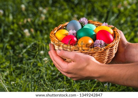 Easter basket with colorful eggs in hands at sunset. Easter holiday 