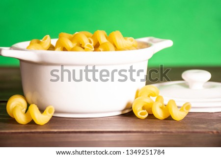 Lot of whole pasta cavatappi in a ceramic stewpan with green screen behind