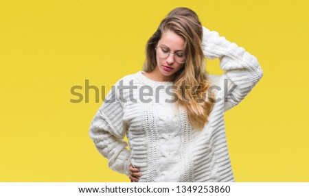 Young beautiful blonde woman wearing winter sweater and sunglasses over isolated background confuse and wonder about question. Uncertain with doubt, thinking with hand on head. Pensive concept.