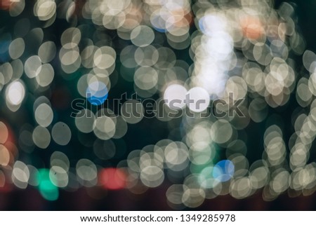 Raindrops on the car windshield with blurred signboard lights along the urban street at night