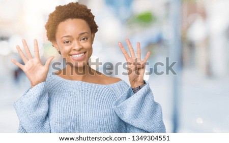 Young beautiful african american woman wearing a sweater over isolated background showing and pointing up with fingers number nine while smiling confident and happy.
