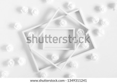 Flowers composition creative. Blank photo frame, white artificial flowers on white background. Flat lay, top view, copy space