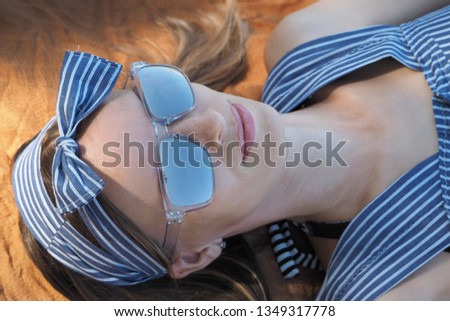 portrait of a girl dressed and wearing sunglasses lying on the beach. relaxing on vacation.